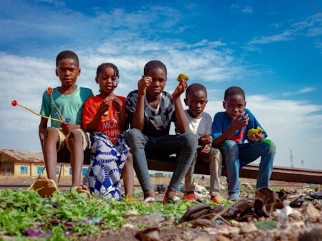 A group of children having fun outdoors in Kaduna, Nigeria, enjoying playtime under a bright sky.